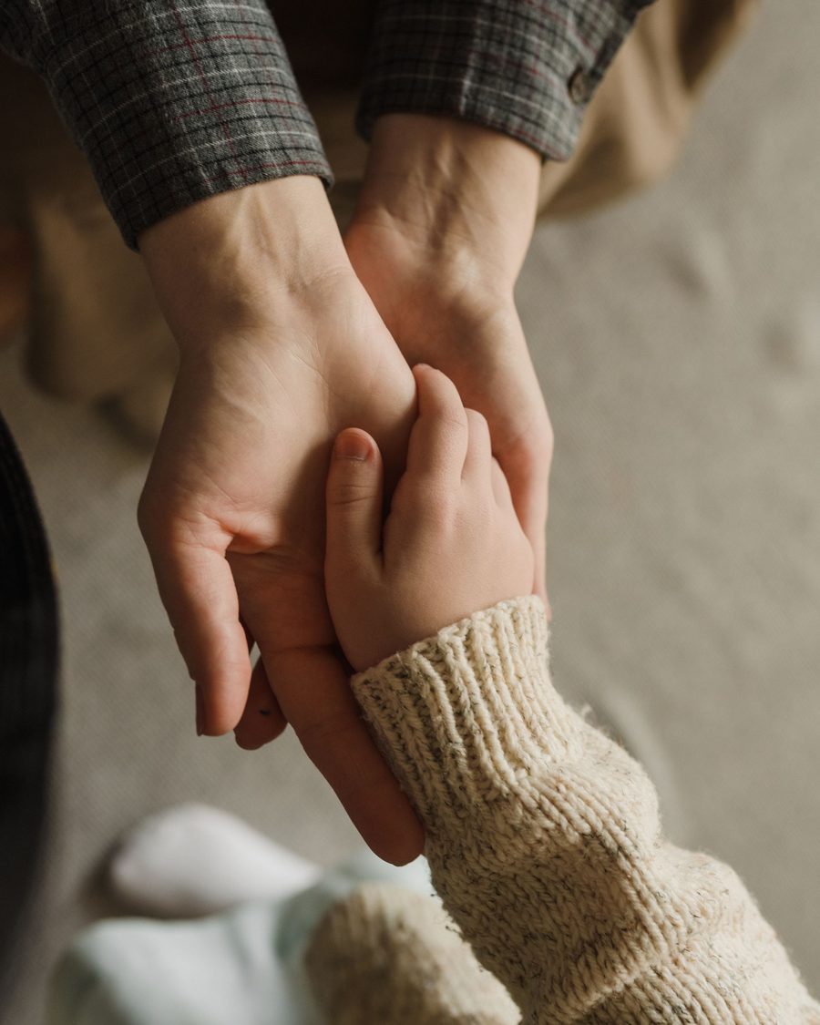 A carer gently holding a child's hand, a moment of warmth and reassurance