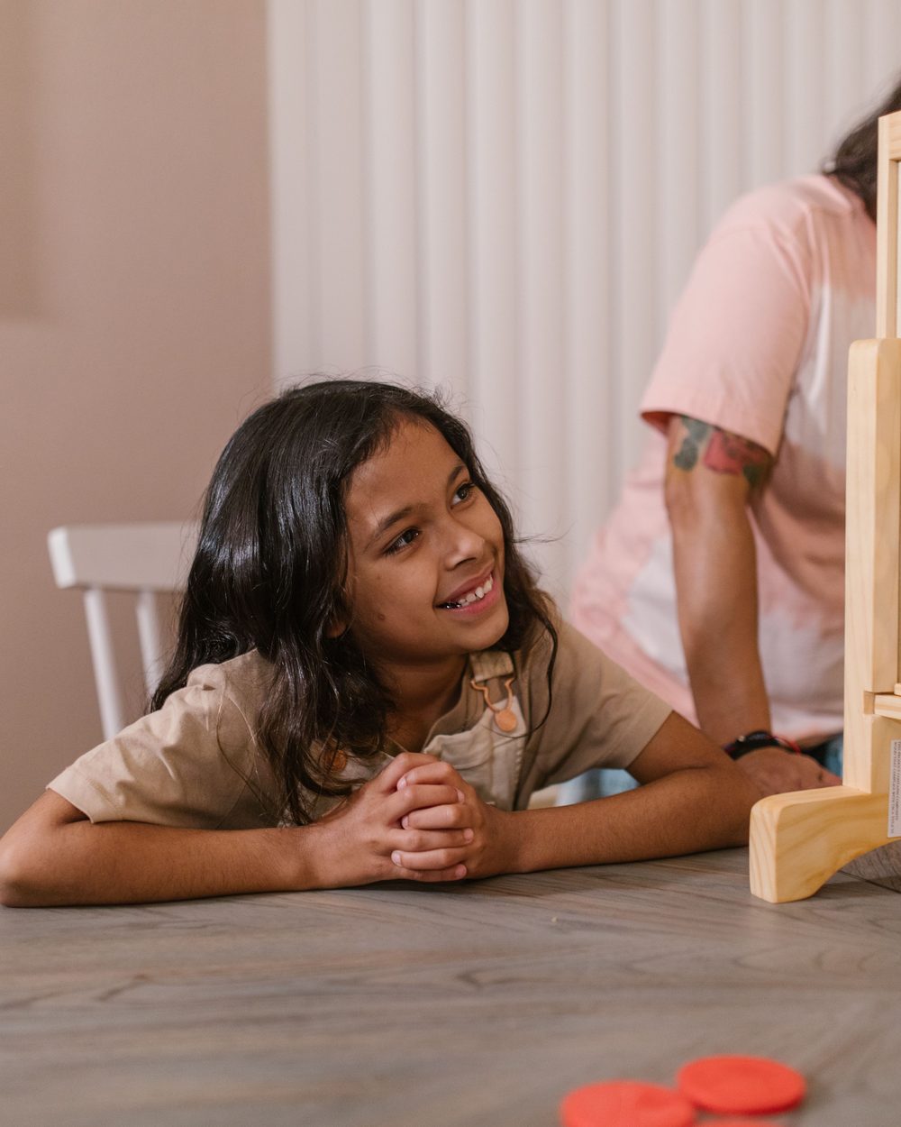 Carer and child mid-laugh over a board game at the kitchen table