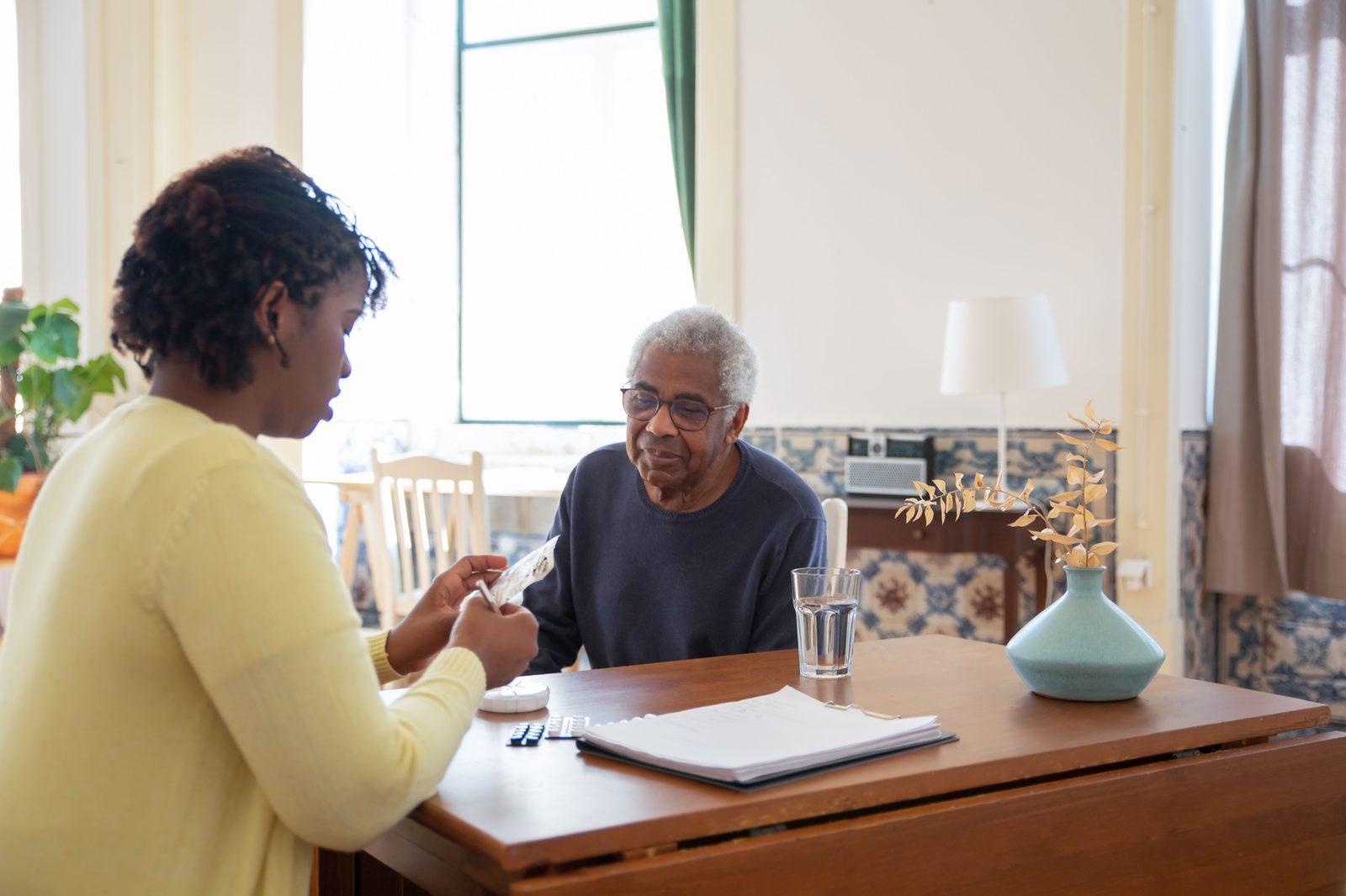 A carer sitting with someone at home, helping them with their medication