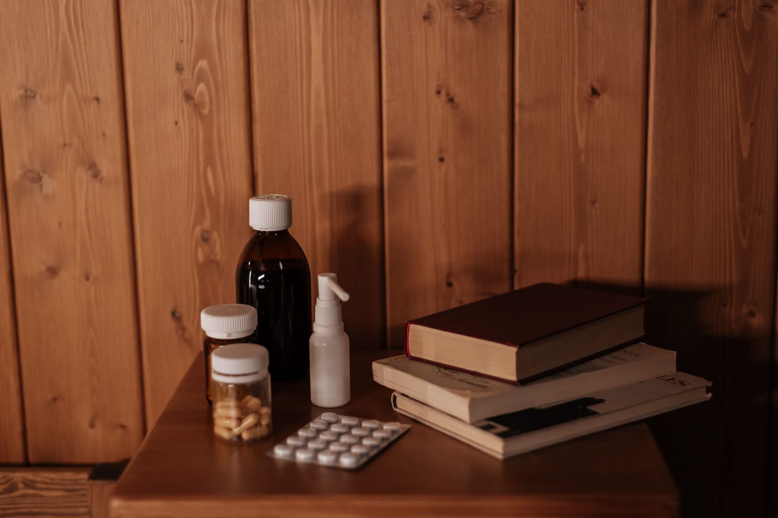 Medication bottles and books on a cosy bedside table