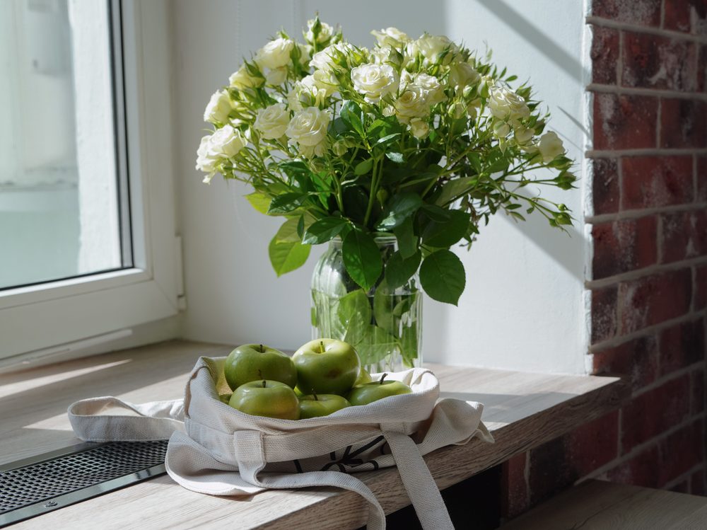 Fresh flowers and apples on a windowsill at home