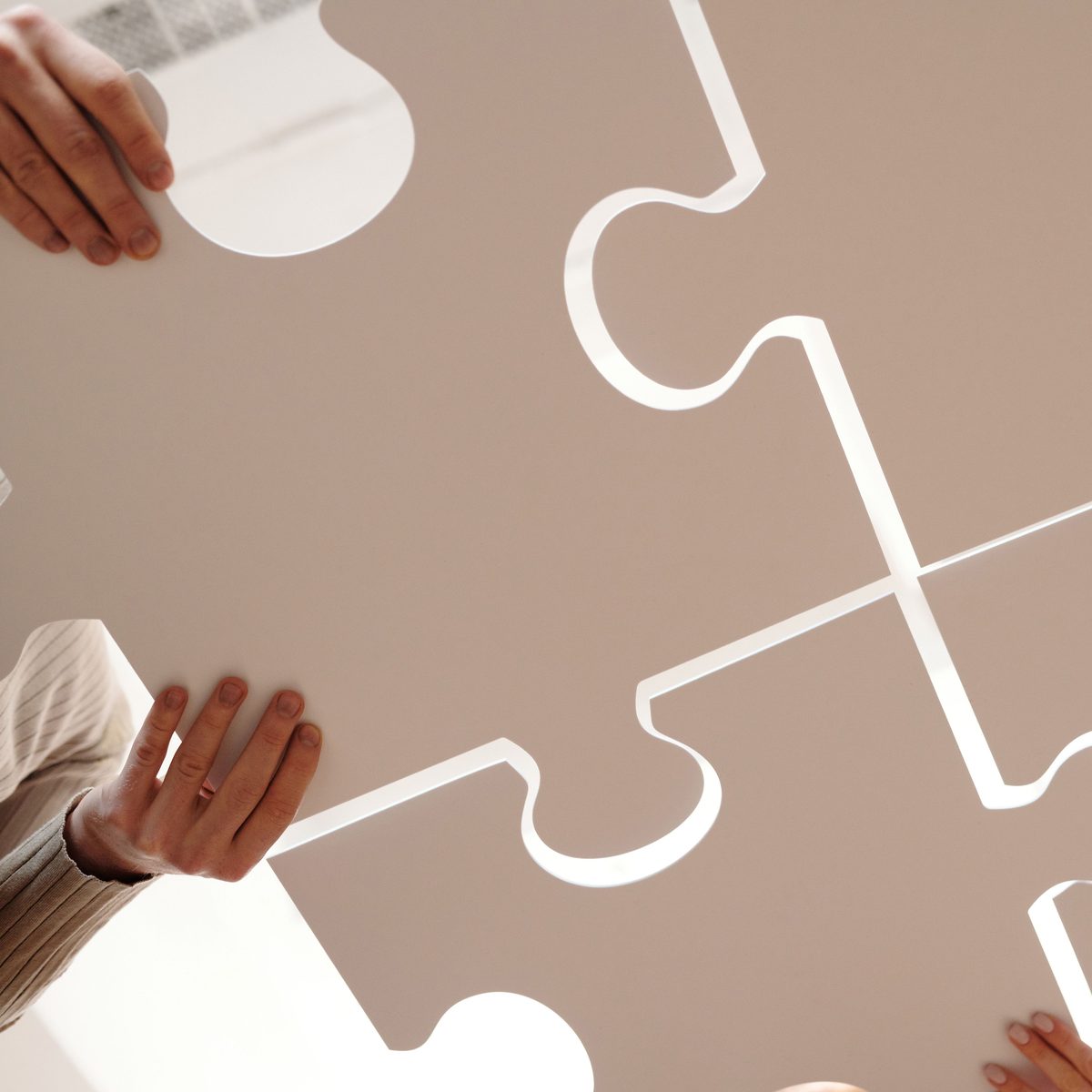 Hands piecing together a jigsaw puzzle at the table