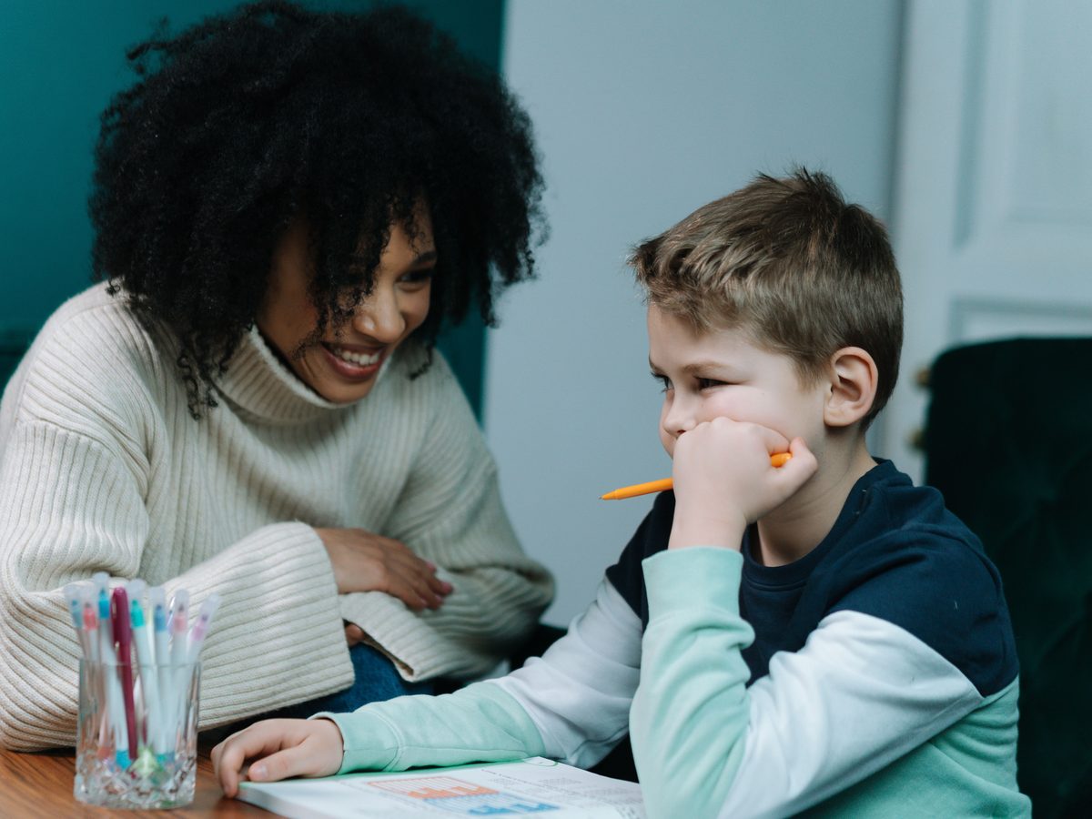 A carer helping a child with homework, both smiling